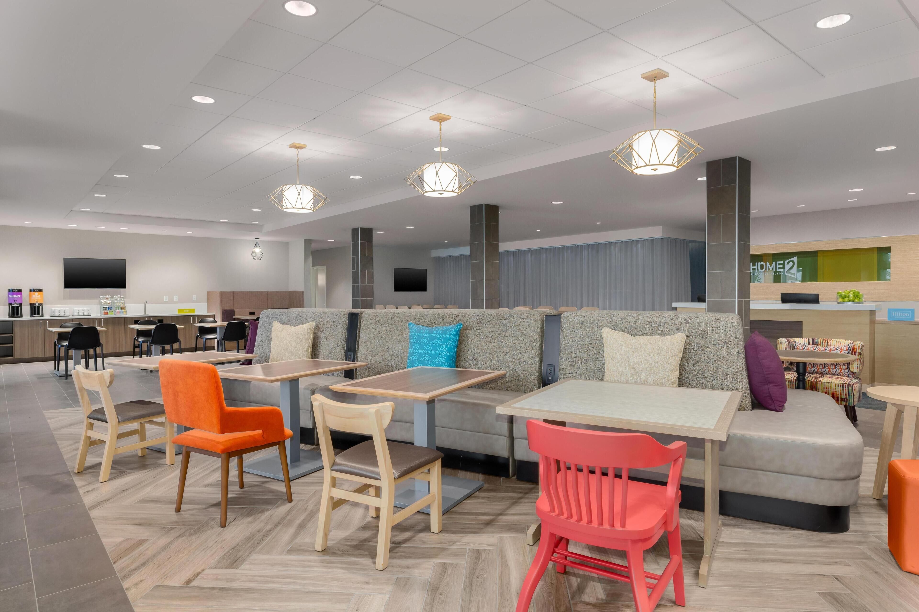 A modern restaurant with seating arrangements including tables and booths, a counter area, and a television screen.
