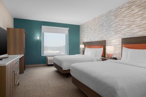 Une chambre d’hôtel avec deux lits, un bureau, une télévision et une fenêtre donnant sur un beau paysage.