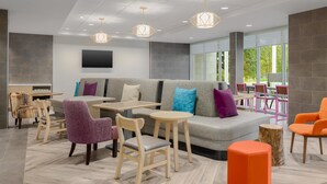 Un espace de détente moderne comprenant un canapé, des fauteuils, des tables et un téléviseur fixé au mur.