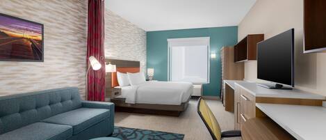 A modern hotel room with a bed, a sofa, a desk, a television, and a window.