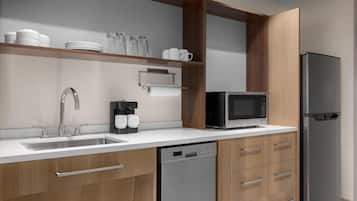 Una cocina moderna con lavavajillas, microondas, refrigerador y armarios de madera.