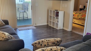 A living room with a grey sofa set, a flat-screen TV mounted on the wall, and a ceiling fan. - 2103 Palms, 2-bedroom condo, Great Fall Weekends are still available (Rehoboth Beach)