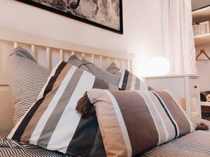 A bed with striped bedding and a headboard, a bedside table, and a hanging light fixture. - Sainte-Anne Sanctuary Old Town (Montpellier)