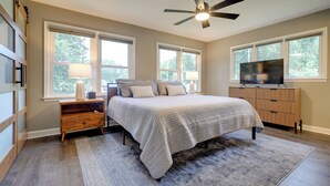 A bedroom with a bed, nightstands, a TV, and a ceiling fan. - Chic Family-Friendly Home in Riverside: 7 Mi to KC (Riverside)