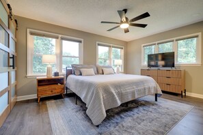 A bedroom with a bed, nightstands, a TV, and a ceiling fan. - Chic Family-Friendly Home in Riverside: 7 Mi to KC (Riverside)