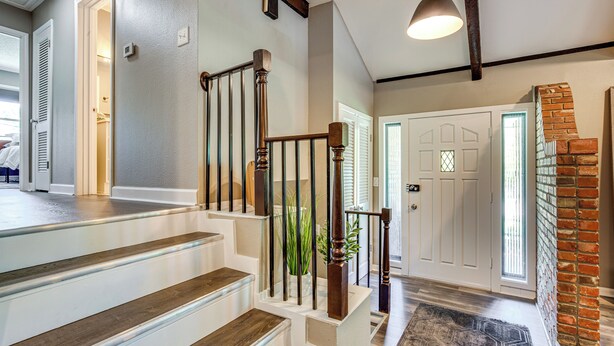 A staircase with wooden steps and metal railings, leading to a landing with a door and a brick wall. - Chic Family-Friendly Home in Riverside: 7 Mi to KC (Riverside)