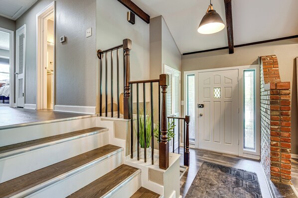A staircase with wooden steps and metal railings, leading to a landing with a door and a brick wall. - Chic Family-Friendly Home in Riverside: 7 Mi to KC (Riverside)