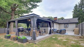 A covered patio with outdoor furniture, a fire pit, and planters. - Chic Family-Friendly Home in Riverside: 7 Mi to KC (Riverside)
