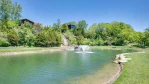 A tranquil pond with a fountain, surrounded by lush greenery and a stone bridge. - Chic Family-Friendly Home in Riverside: 7 Mi to KC (Riverside)
