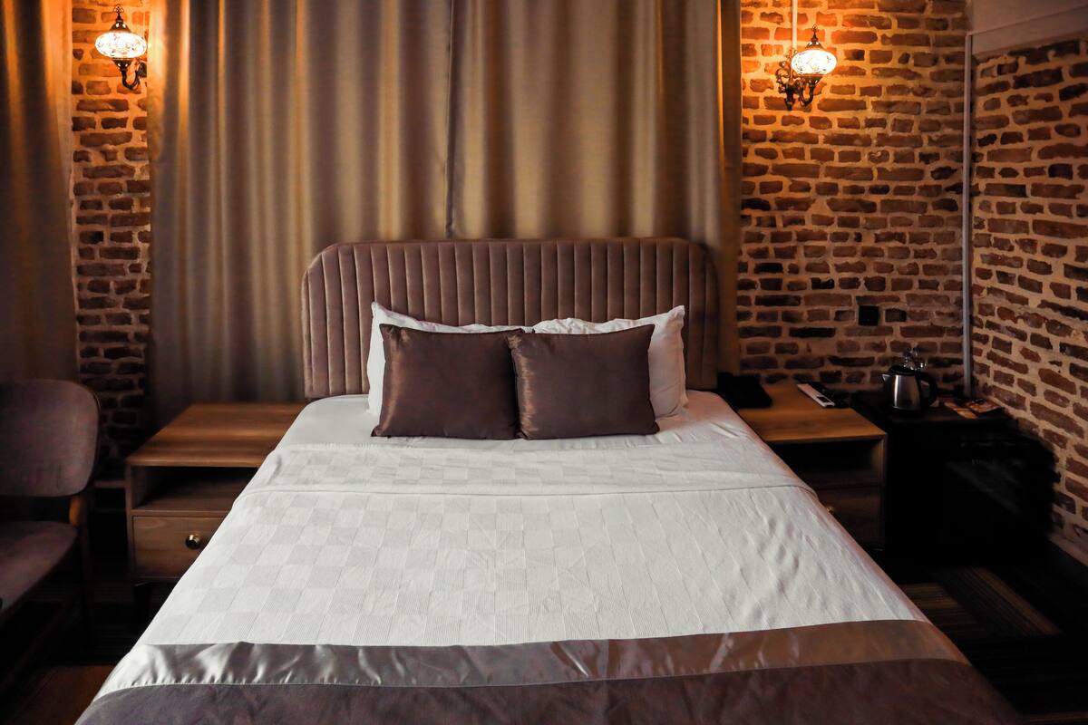 A neatly made bed with a headboard, two bedside tables, and a lamp on each side.