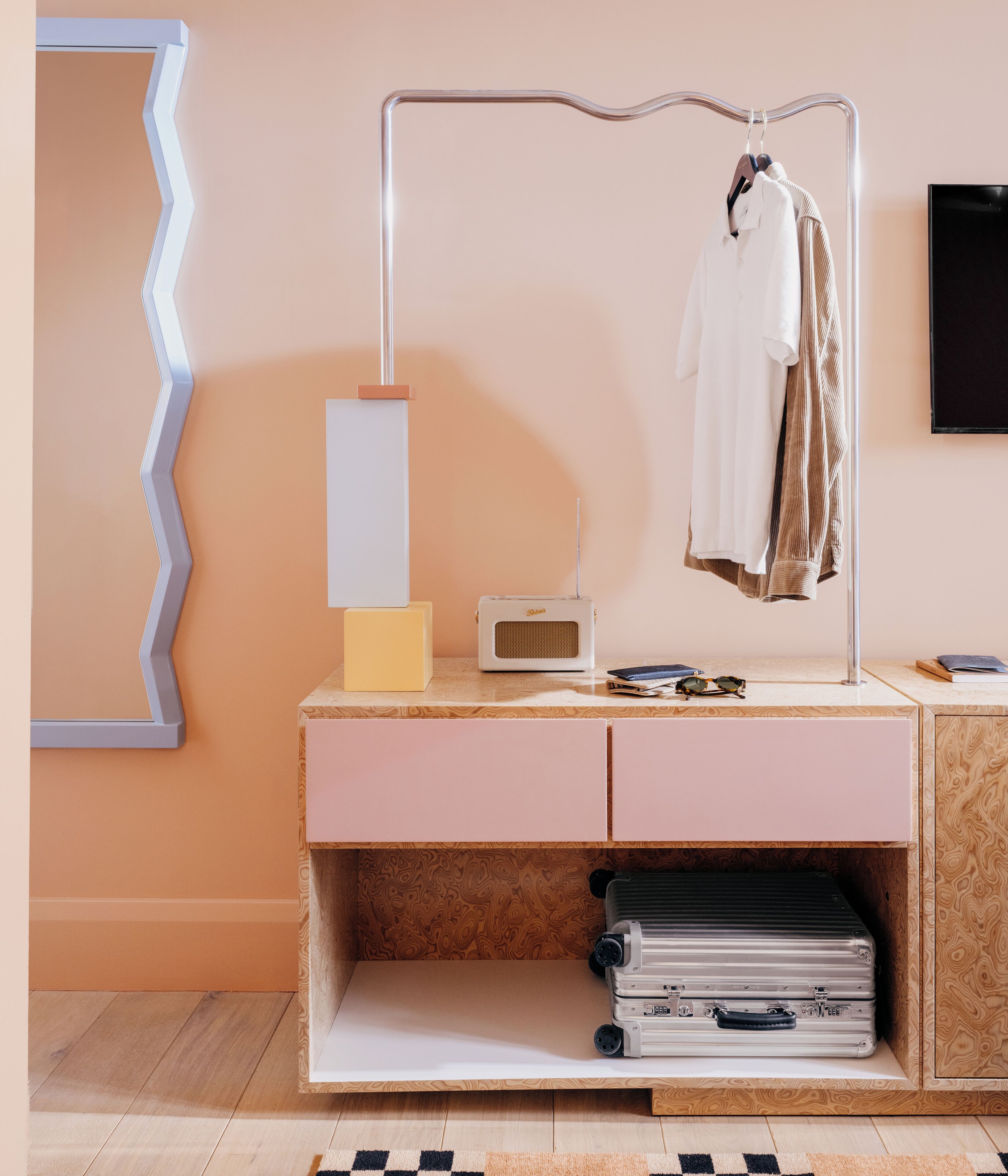 A modern room with a wooden dresser, a radio, and a clothing rack.