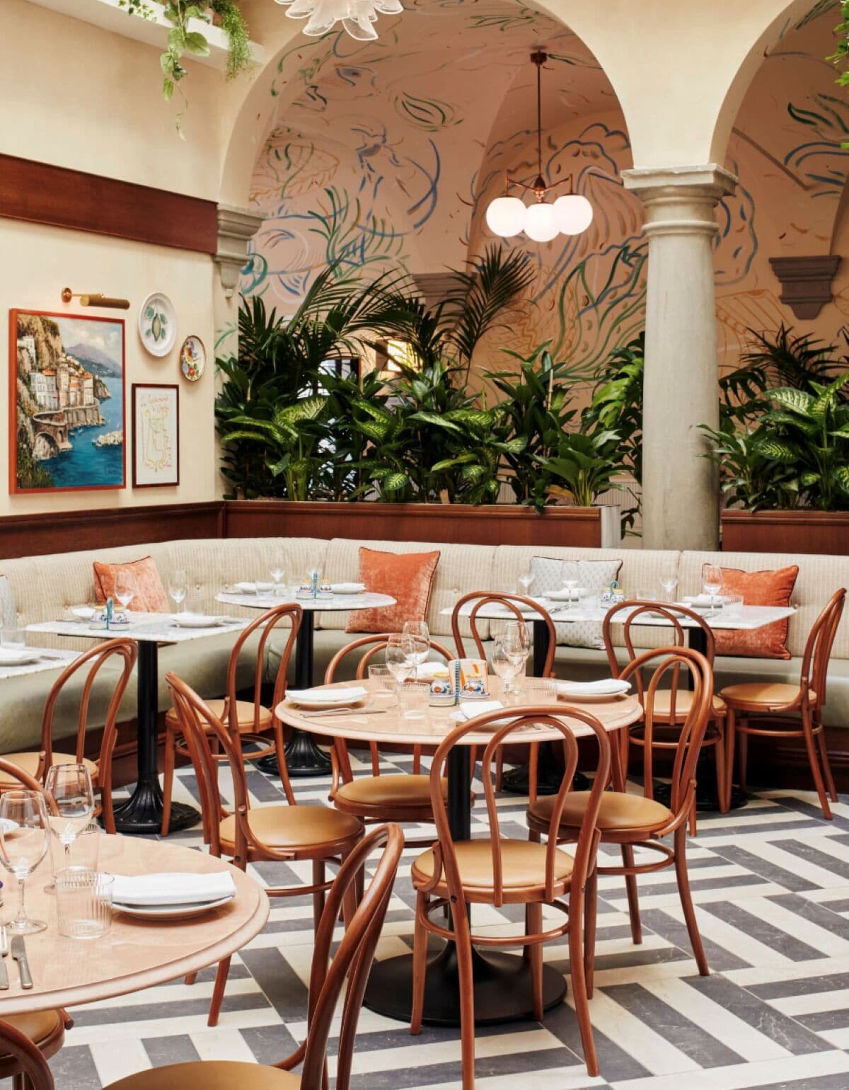 A restaurant with round tables and chairs, a checkered floor, and a mural on the wall.
