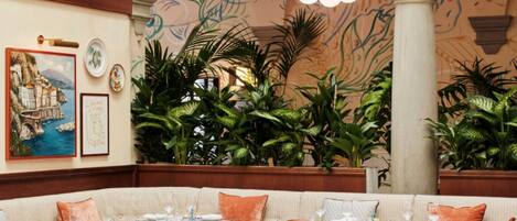 A restaurant with round tables and chairs, a checkered floor, and a mural on the wall.