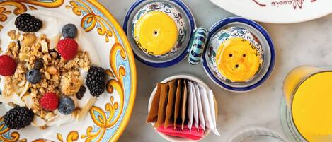Un desayuno con diferentes platos, como panqueques, huevos y una ensalada de frutas.