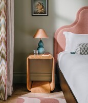 Una camera da letto ordinata con un letto, un comodino con una lampada, un bicchiere d'acqua e un quaderno.