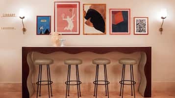 A reception area with a counter, four bar stools, and framed artwork on the wall.