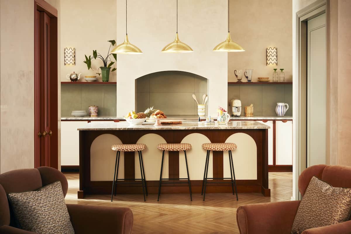 A kitchen with a central island, bar stools, pendant lights, and a fireplace.
