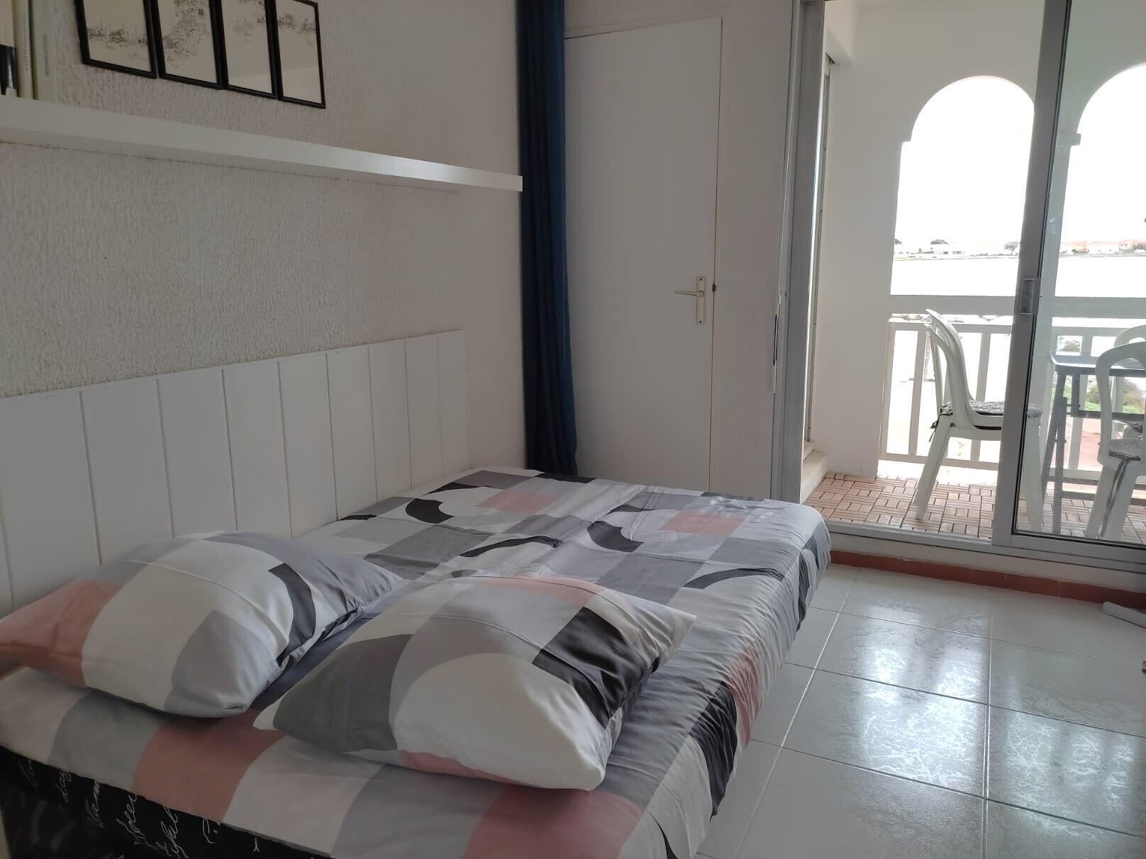 Un dormitorio con cama, ventana y vistas al exterior.