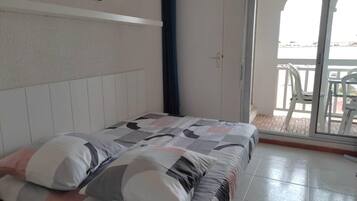 Un dormitorio con cama, ventana y vistas al exterior.