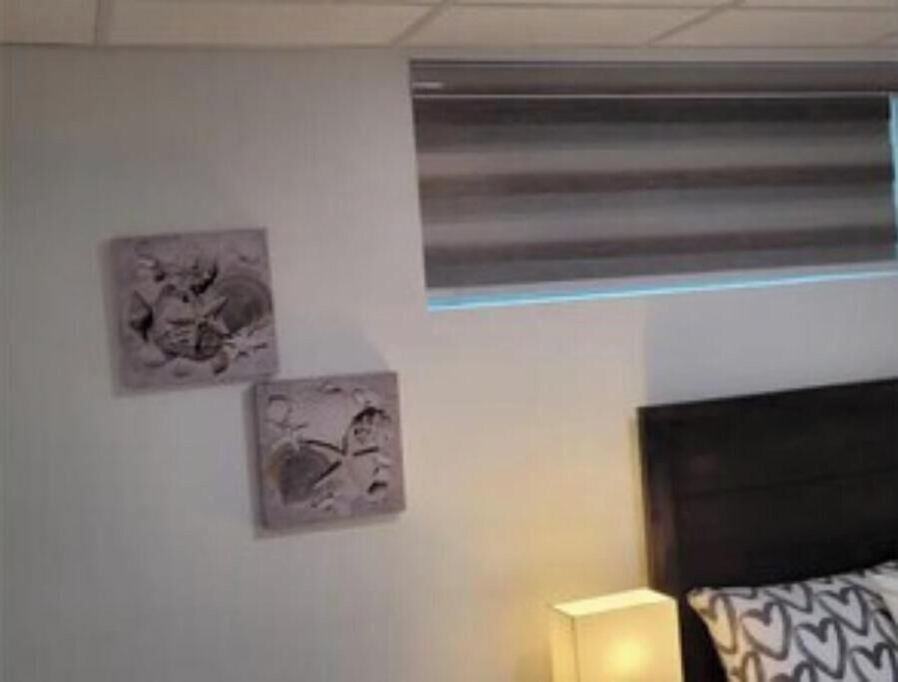 A hotel room with a bed, a nightstand, and two wall-mounted artworks.
