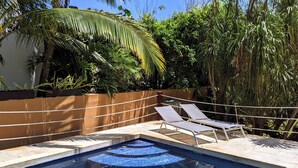 Una piscina con due lettini prendisole e una vasca idromassaggio.