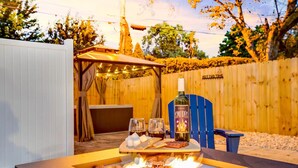 A backyard with a fire pit table, a bottle of wine, and a covered seating area. - 1 Mile to Notre Dame, Hot Tub, 2400 Sq Ft (South Bend)