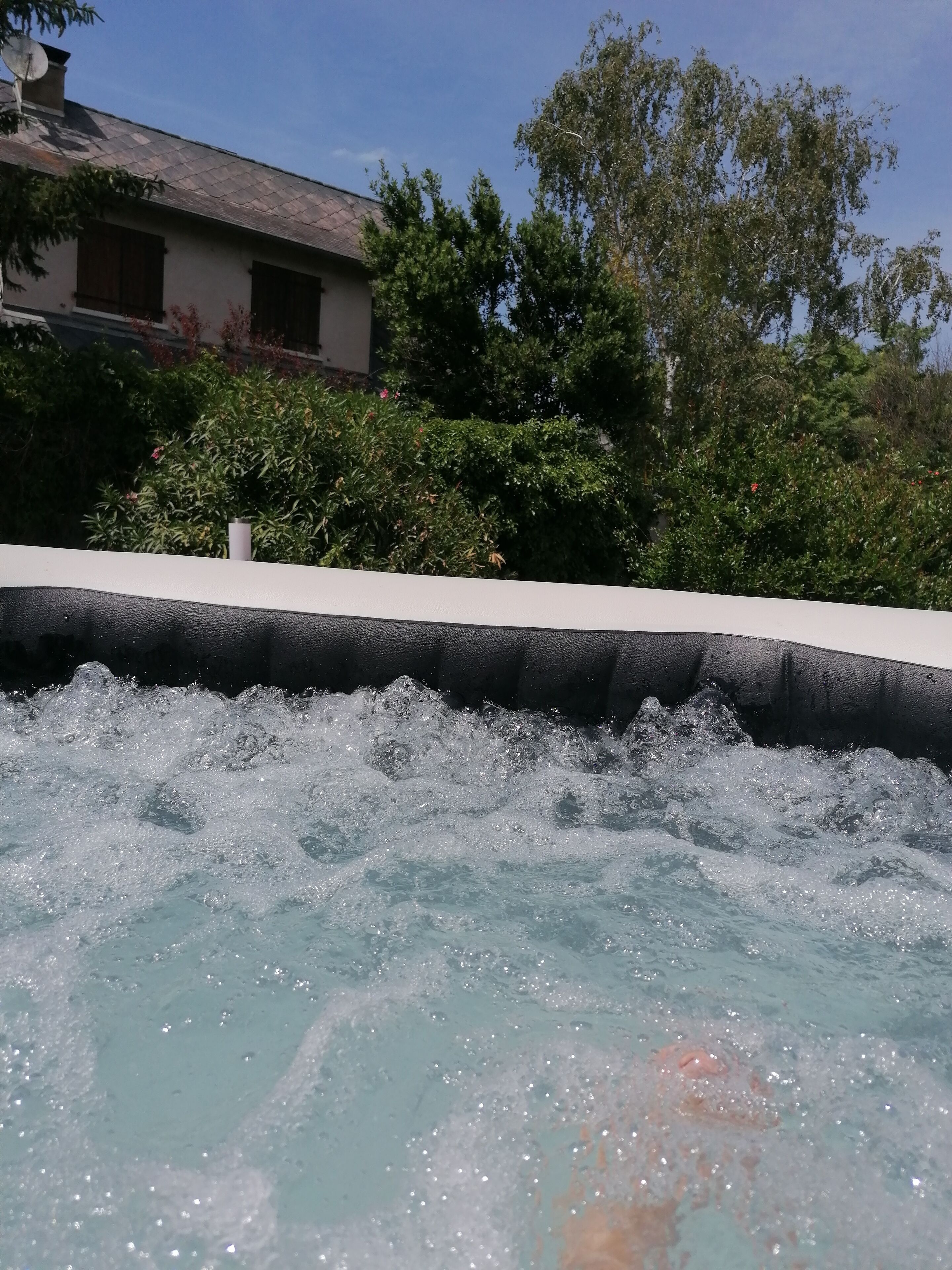 A hot tub with a view of a building and trees in the background.