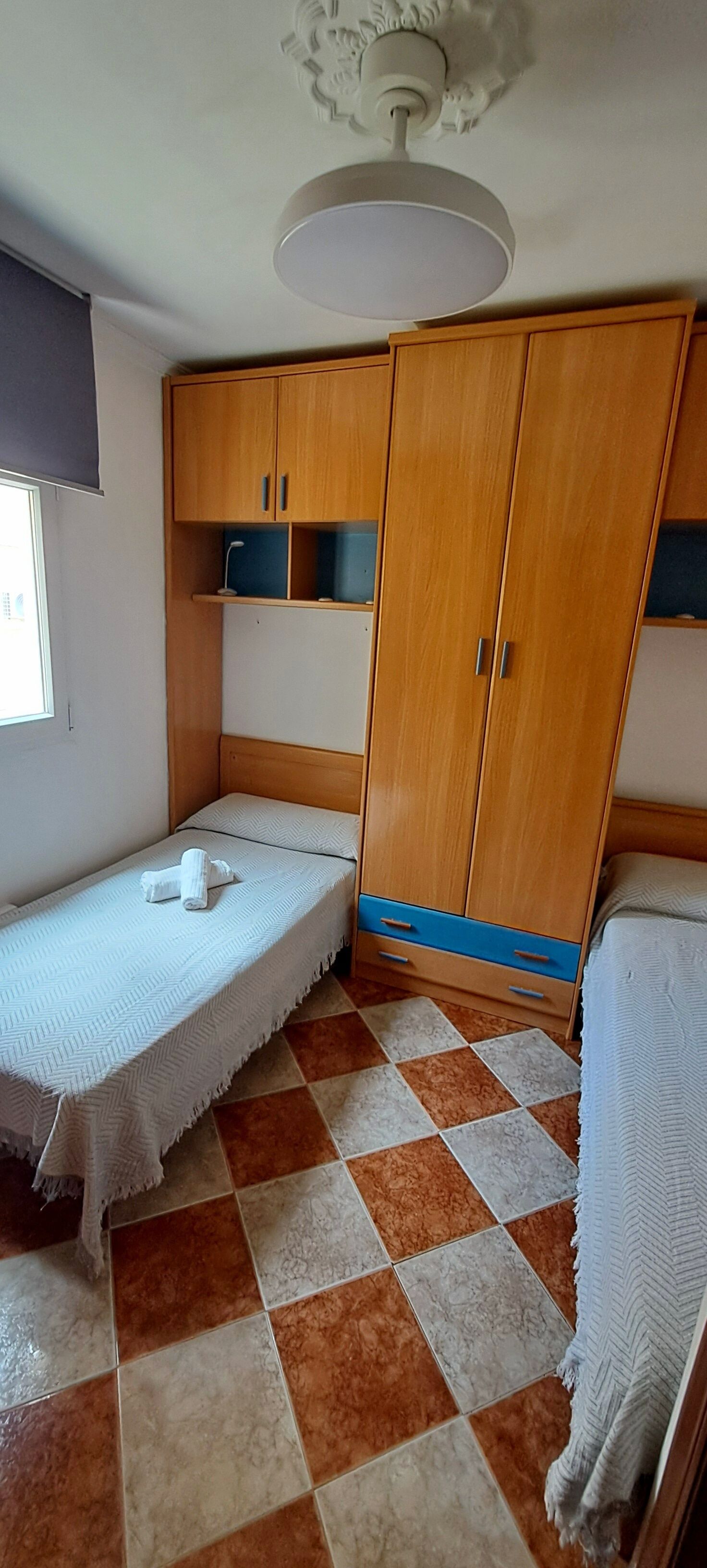 Una habitación pequeña con cama, armario y ventilador de techo.
