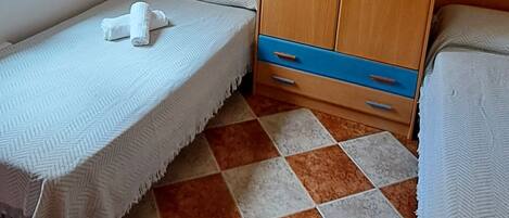 Una habitación pequeña con cama, armario y ventilador de techo.