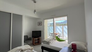 Une chambre à coucher comprenant un lit, un bureau, une chaise, un téléviseur et une fenêtre donnant sur l’extérieur.
