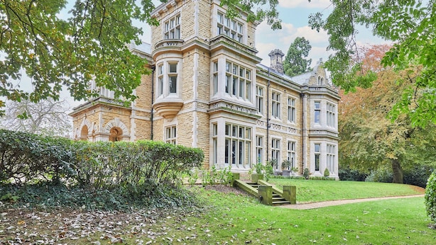 A large, historic building with a prominent corner tower, surrounded by lush greenery and a well-maintained lawn. - Highfield House (Ripon)