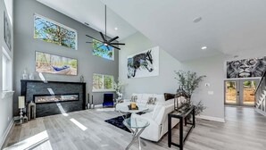 A spacious living room with a fireplace, a sofa, a coffee table, and artwork on the walls. - Catalytic Derby themed (Helen)