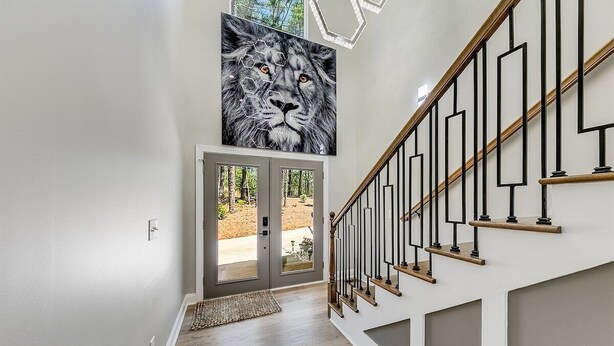 A staircase with a wooden handrail and black balusters, leading to a door with glass panels. - Catalytic Derby themed (Helen)