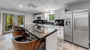 A modern kitchen with a bar area, stainless steel appliances, and large windows. - Catalytic Derby themed (Helen)