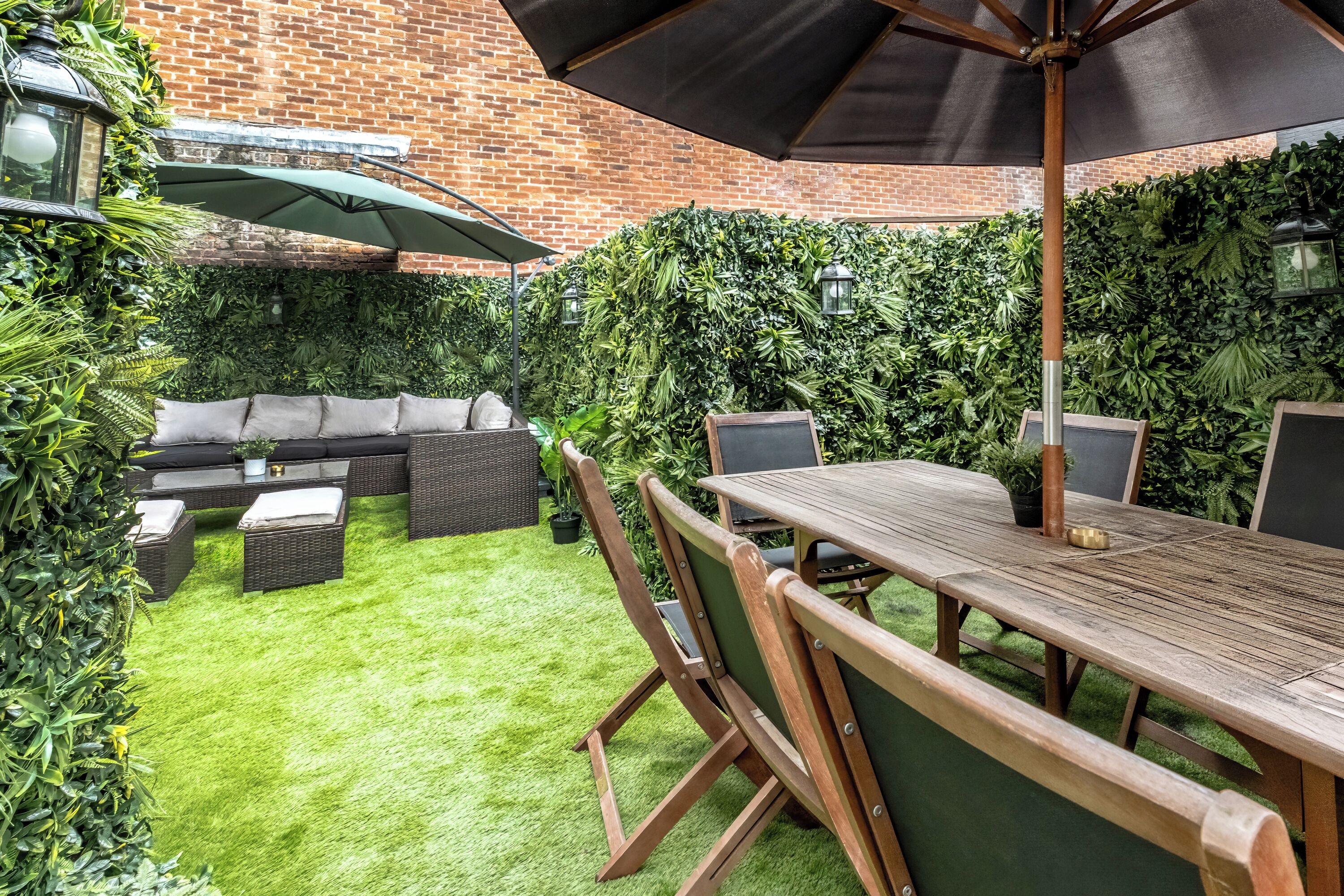 A patio with a wooden table and chairs, a sofa, and an umbrella.