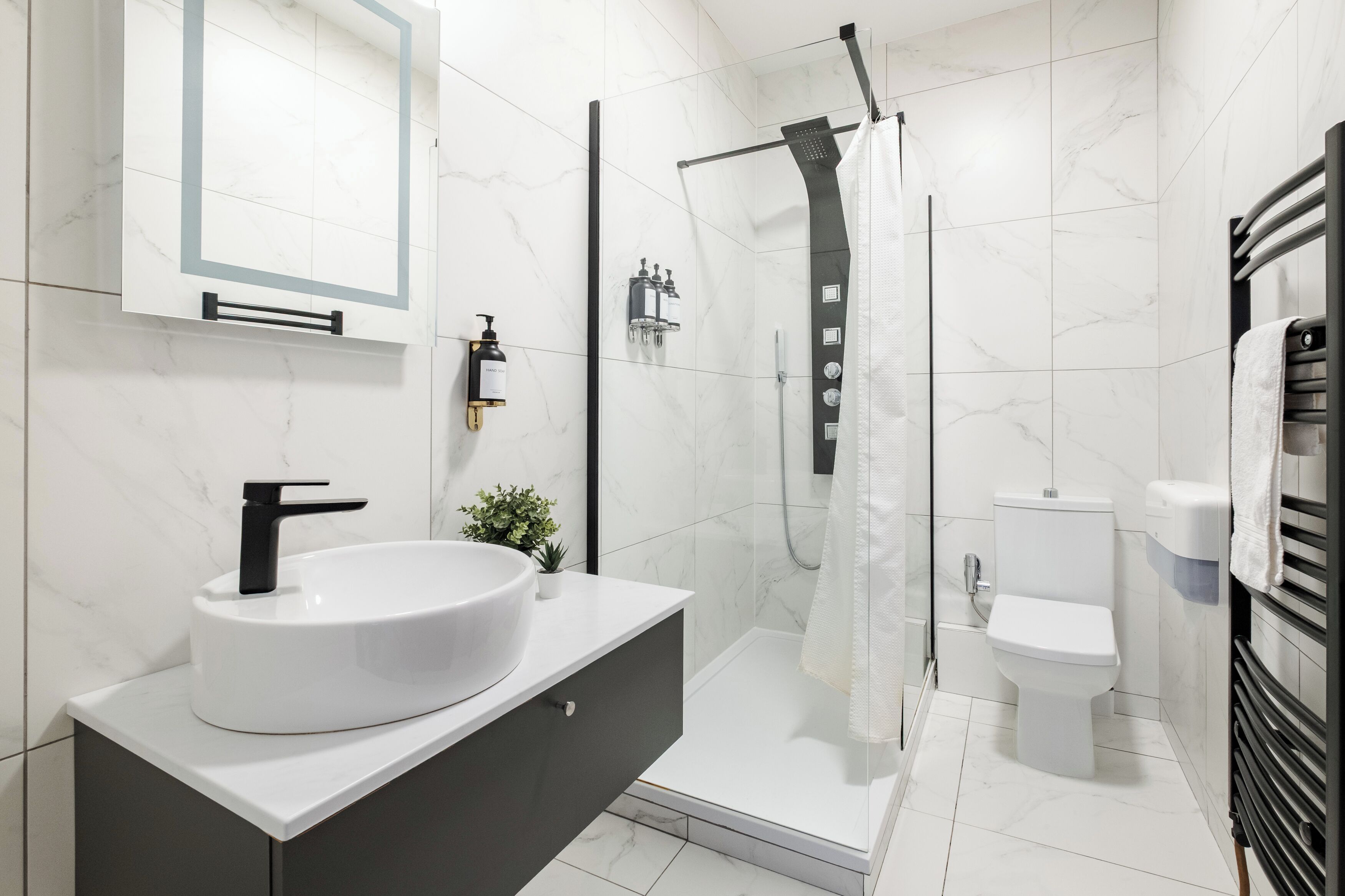 A modern bathroom with a white sink, black faucet, and a glass-enclosed shower.