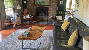 A cozy living room with a fireplace, leather sofa, wooden coffee table, and a brick wall.