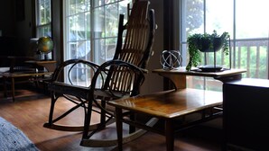 A room with a rocking chair, a wooden table, and a potted plant on a windowsill.