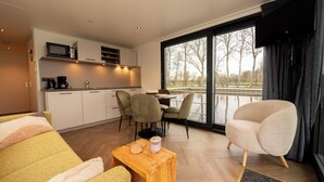 Une chambre d’hôtel moderne dotée d’une cuisine, d’un coin repas et de grandes fenêtres.
