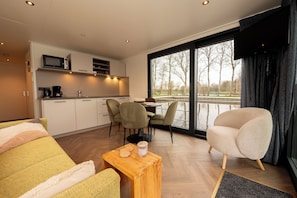 A modern hotel room with a kitchen, dining area, and large windows. - Houseboat - Paviljoenwei 4 | Sneek (Offingawier) (Offingawier)