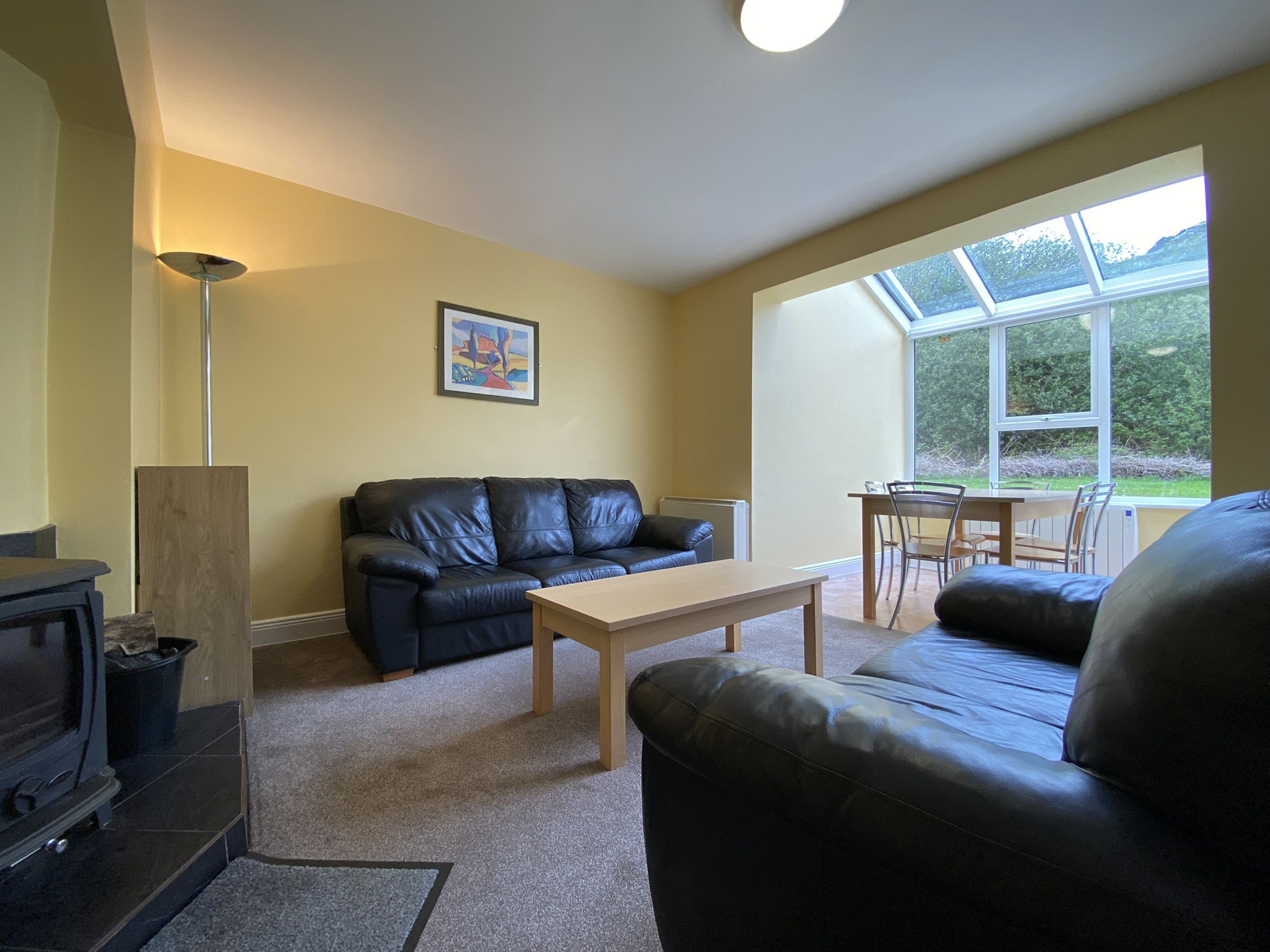 A living room with a sofa, a coffee table, a fireplace, and a dining area with a table and chairs.