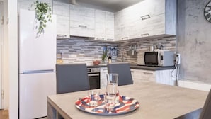 Uma cozinha moderna com armários brancos, painel de azulejos e um micro-ondas.