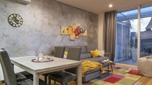 Uma sala de estar moderna com uma mesa de jantar, sofá e uma janela grande.