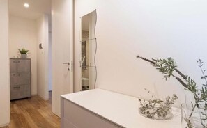 Bathroom features a large mirror, a small cabinet, and a countertop with a vase.