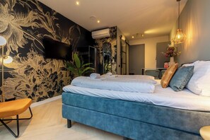 Un dormitorio moderno con una cama grande, un televisor de pantalla plana montado en la pared y un equipo de aire acondicionado instalado en el techo.