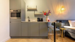 A modern kitchen with grey cabinets, a built-in oven, and a coffee maker on the counter. - Studio - Van der Manderelaan 16 'Studio B' | Koudekerke (Koudekerke)