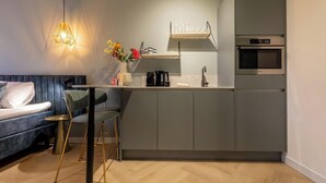 Una cocina moderna con gabinetes grises, horno integrado y máquina de café.