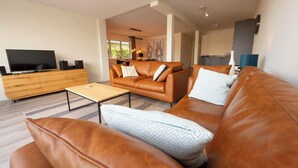 Un salon moderne avec un canapé en cuir, une table basse et un téléviseur posé sur un meuble en bois.