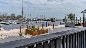 Un port de plaisance avec des bateaux amarrés, une terrasse en bois et un espace aménagé avec vue sur l’eau.