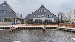 Une propriété située au bord d’un canal, comprenant deux maisons, un quai et un petit bateau.
